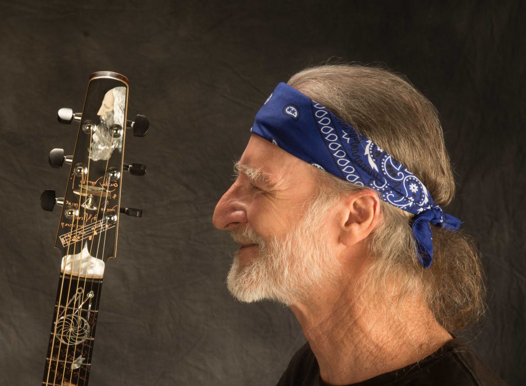 Man with guitar, wearing blue bandana.