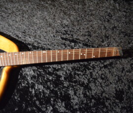 Electric guitar neck on textured black background.