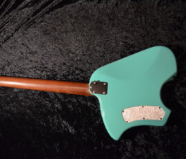 Back of teal electric guitar on fabric.