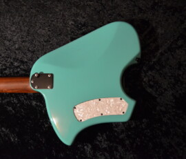Turquoise guitar body on dark textured background.