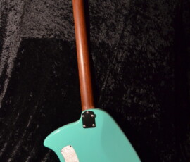 Turquoise electric guitar body on black background.