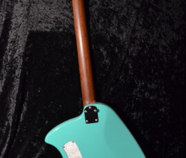 Back of teal electric guitar on black.