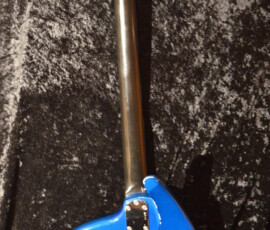 Blue electric guitar on dark textured background.