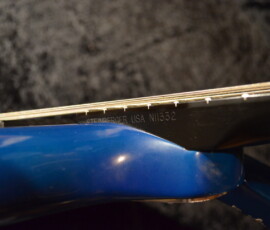 Close-up of blue guitar neck and strings.