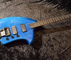 Blue electric bass guitar on dark fabric.