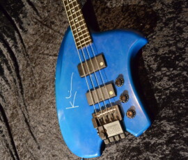Blue electric bass guitar on textured fabric.