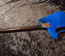 Blue electric guitar on textured surface.