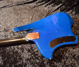 Blue electric guitar on textured black surface.