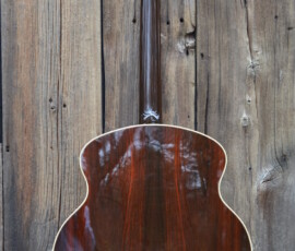 Back of acoustic guitar against wooden background.