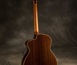 Back view of acoustic guitar against backdrop.