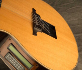 Acoustic guitar with electronic tuner attached.