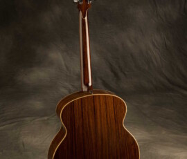 Acoustic guitar back view against dark background.