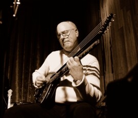 Musician playing guitar on a dimly lit stage.