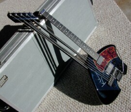 Electric guitar leaning against silver case.