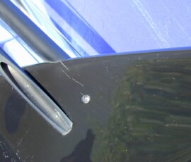 Close-up of scratched black car panel.