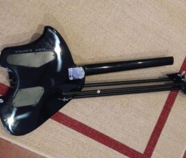 Black electric guitar on patterned carpet.