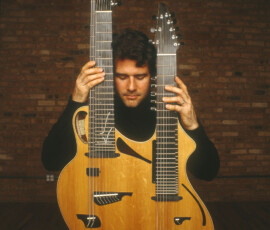Man holding a double-necked guitar instrument.